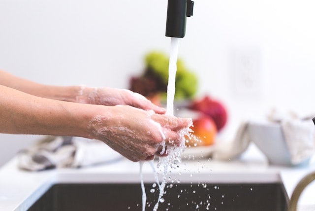 person washing hands at the kitchen sink